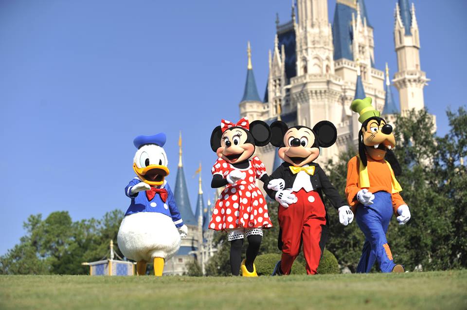 Imagen de los personajes de Disney Minie, Mickey y Pato Donald caminando por el parque de diversiones