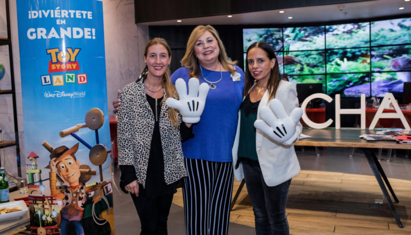 Imagen de tres mujeres, directivas de COCHA y Disney, mostrando los clásicos guantes blancos de Mickey Mouse