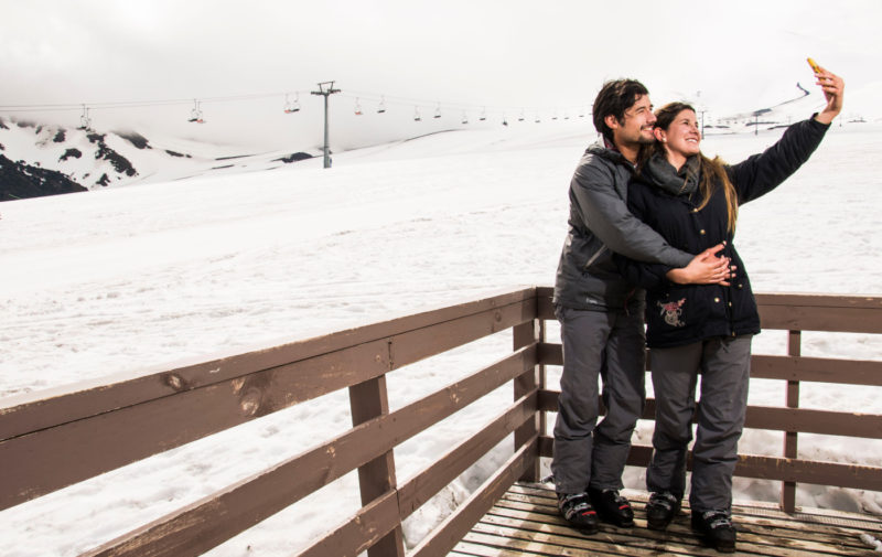 Imagen de una pareja románticamente abrazados tomandose fotografías en Valle Nevado
