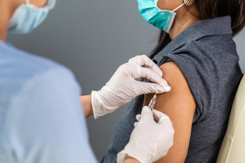 Personal de salud vacunando brazo mujer